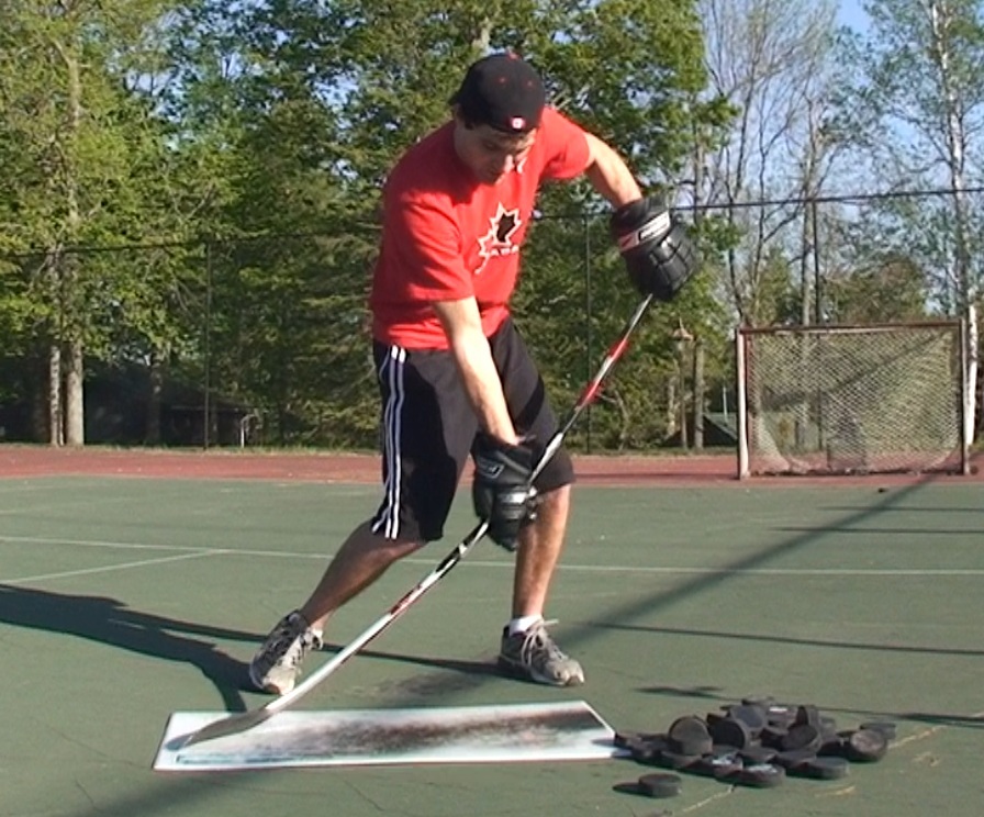 Hockey player practicing shot outside on a tennis court