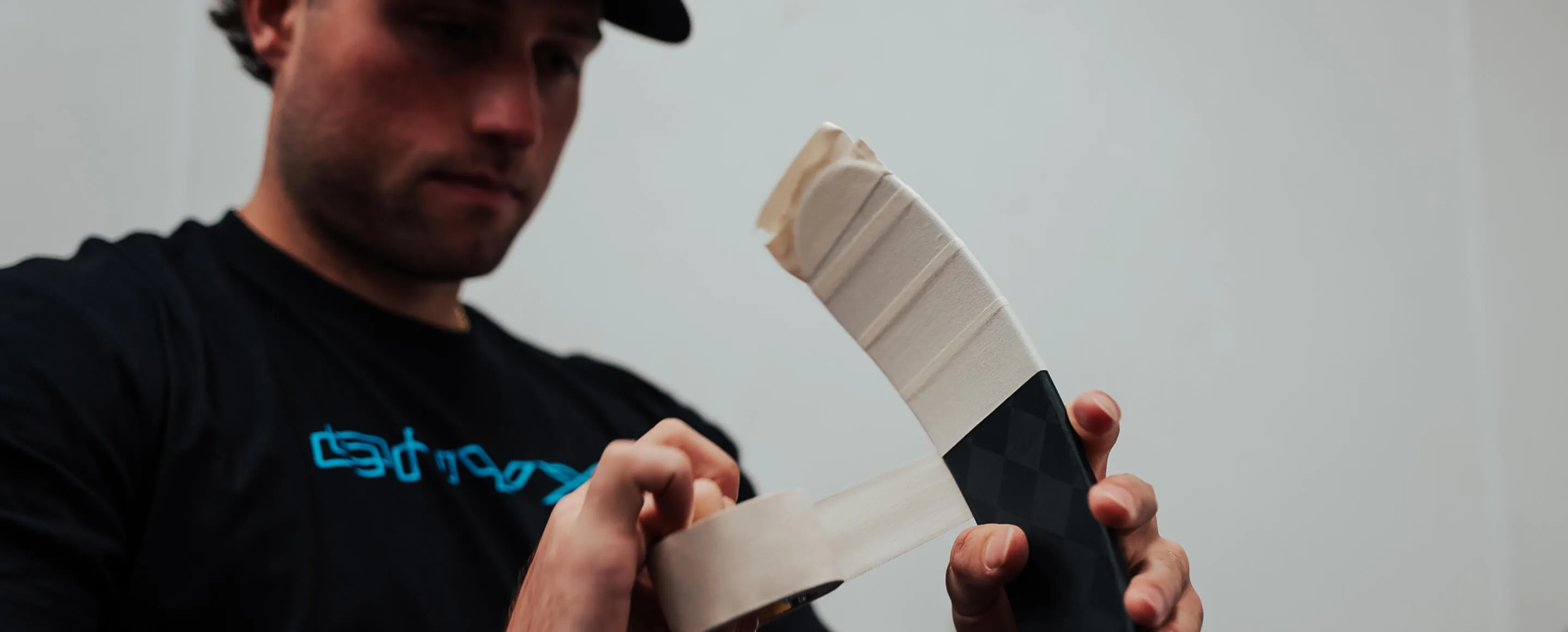 Applying a fresh roll of hockey tape to a stick blade