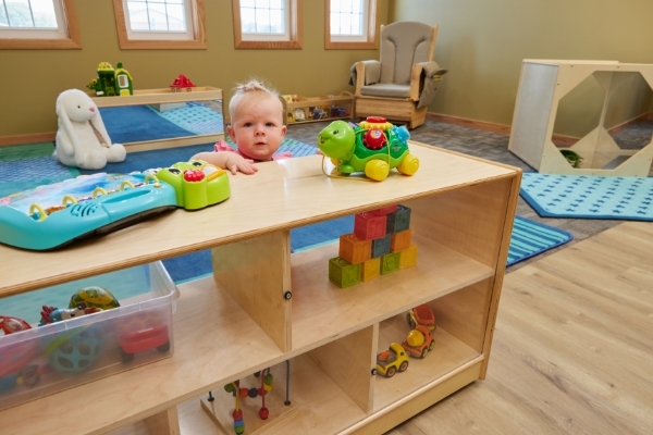 Baby standing, looking over shelf