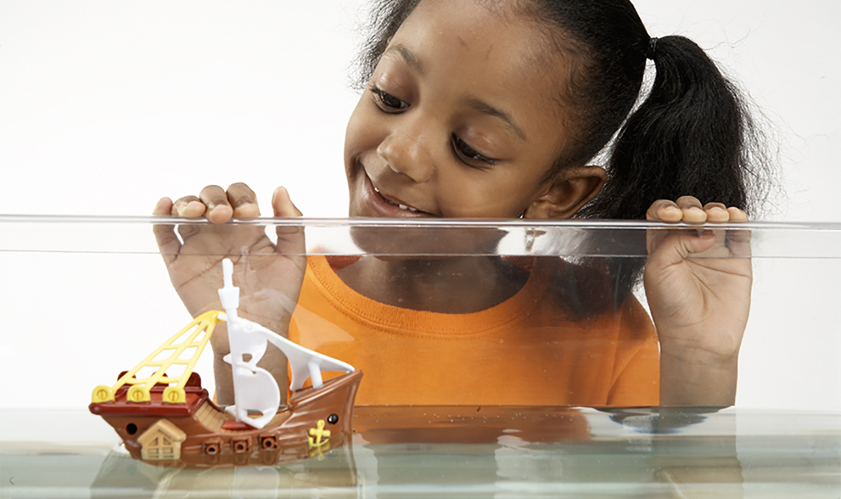 Girl looking into water tank with ship inside