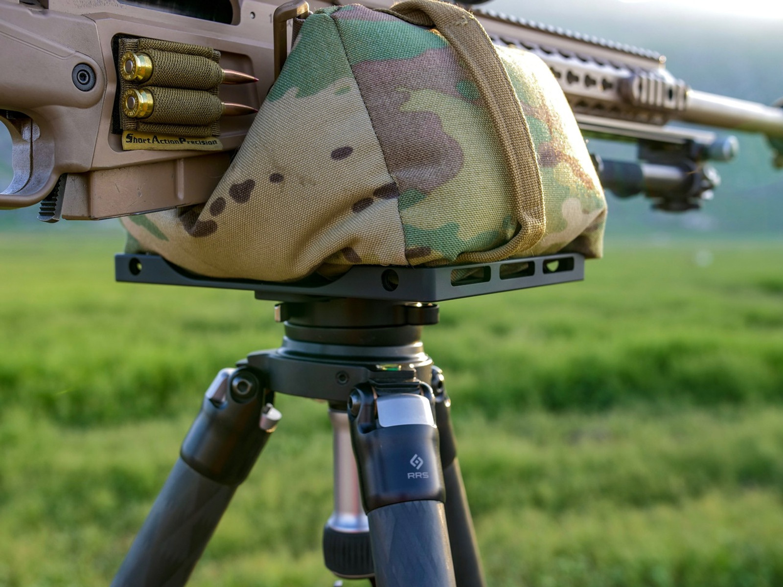 Image of the Abel Table being used in a green field on a tripod with a shooting bag and rifle resting on top of the Abel Table.