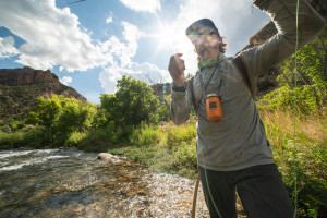 Man fishing in nature with orange can holder hanging around his neck