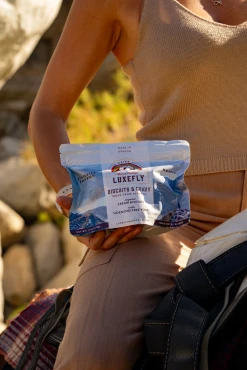 show a person holding the Luxefly Basecamp Biscuit and Gravy, showing the tear-away top and Mylar plastic pouch