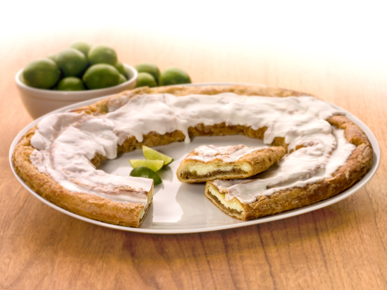Key Lime Kringle on a white plate with slices of limes and bowl of limes.