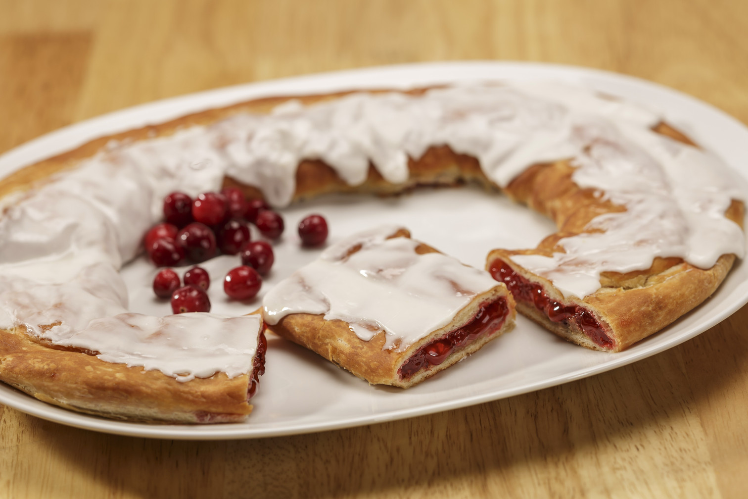 Cranberry Kringle on white plate with a scattering of cranberries.