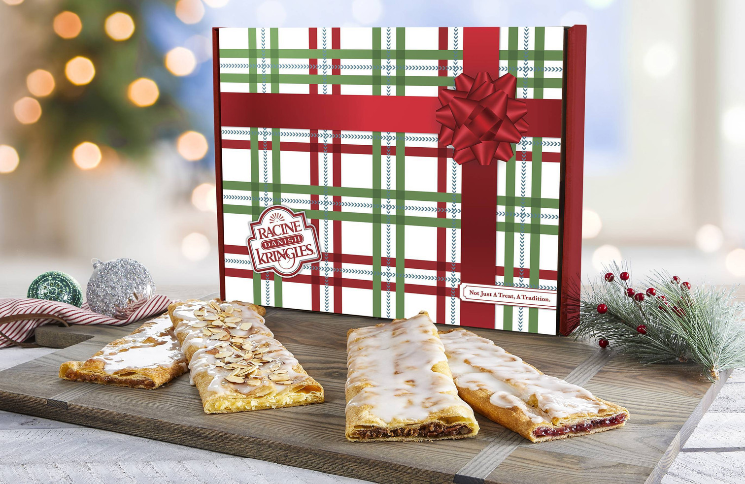 The Classic Stick Sampler in a Holiday Box with Kringles in front of the box on a wooden cutting board.