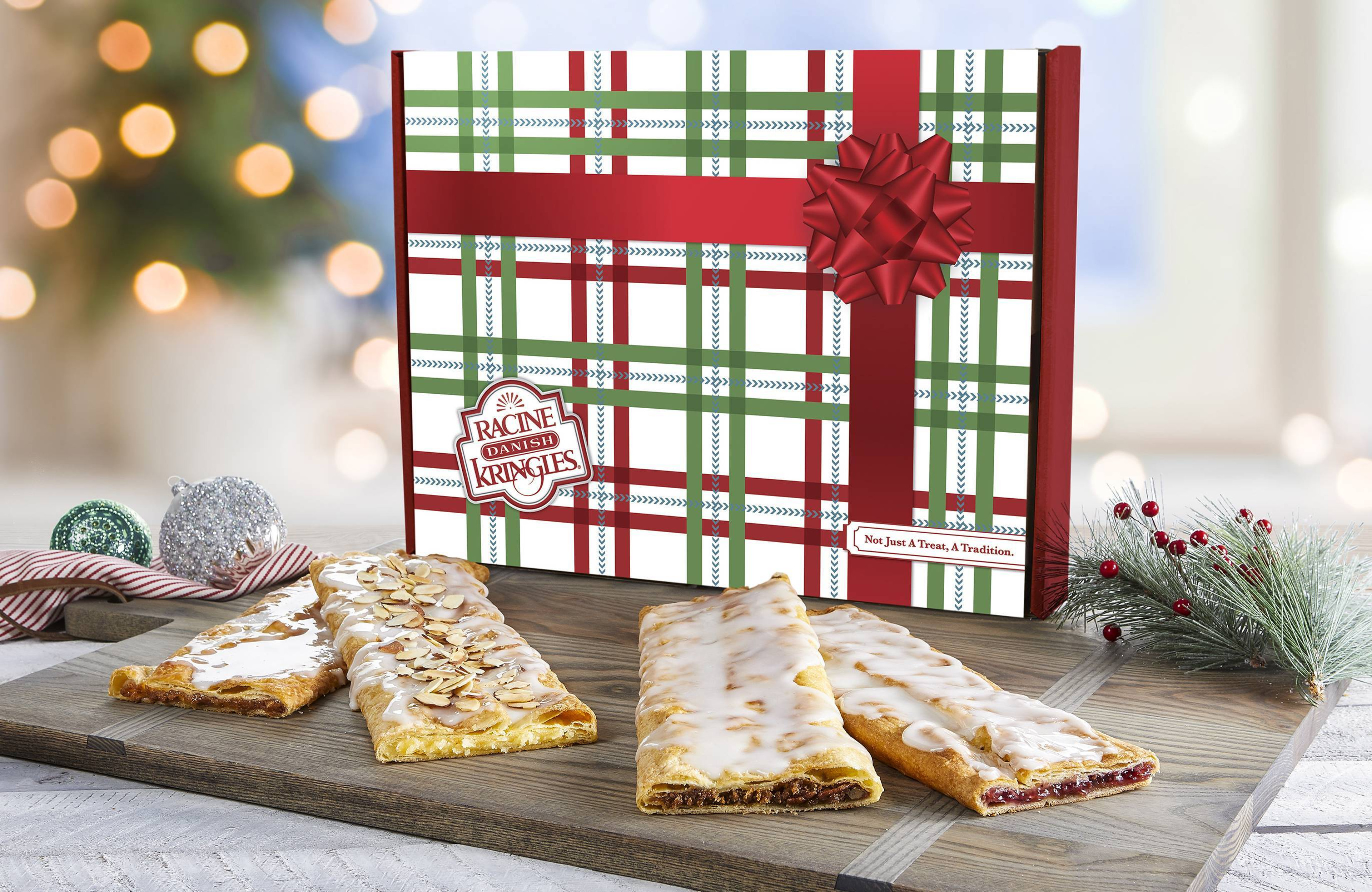 The Classic Stick Sampler in a Holiday Box with Kringles in front of the box on a wooden cutting board.