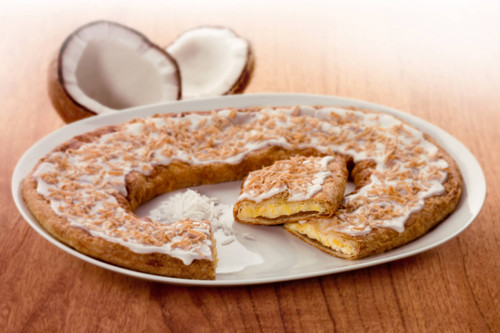 Coconut Kringle of a white plate with coconut shavings and coconut halves.