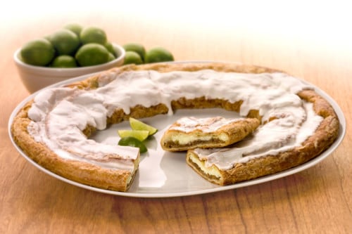 Key Lime Kringle on a white plate with slices of limes and bowl of limes.