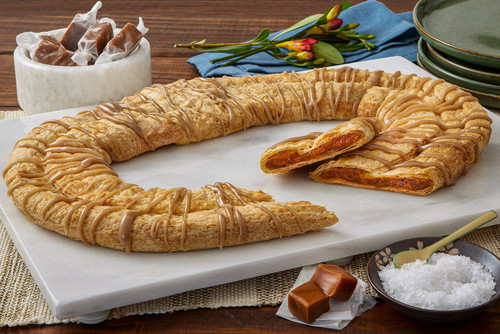 Sea Salt Caramel Kringle sitting on a marble cutting board with caramels near the kringle.