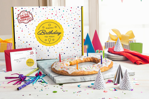 Happy Birthday Gift Box with a Birthday Kringle in front on a marble cutting board with party favors near the Kringle.