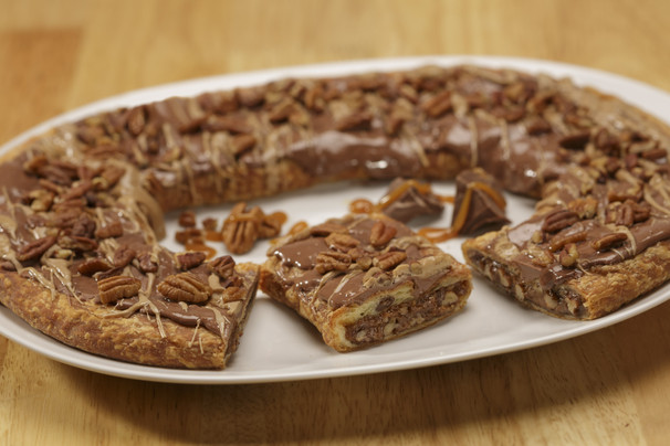 Turtle Kringle on a white plate with chocolate chunks drizzled with caramel.