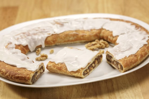 Walnut Kringle on white plate with scattering of walnuts.