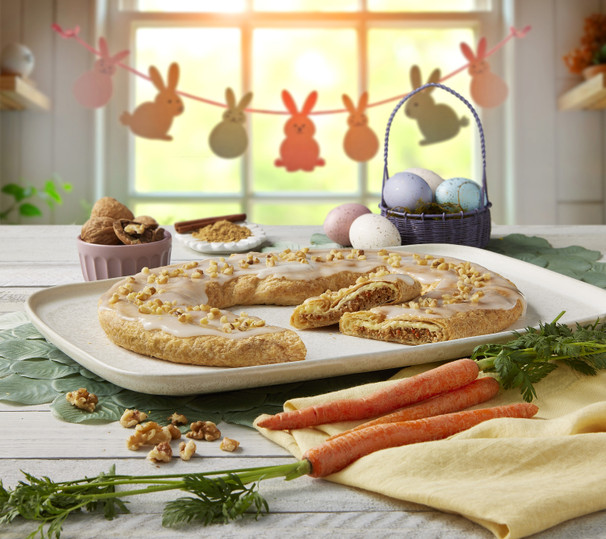 Carrot Cake Kringle on white plate surrounded by colored eggs and carrots.