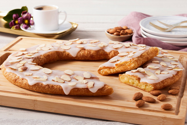 Almond Kringle sitting on a cutting board with a few almonds next to the Kringle.