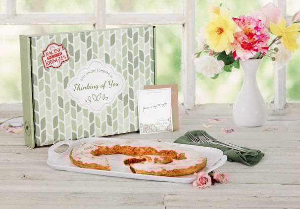 Kringle on a white plate in front of a Thinking of You Gift Box with flowers.