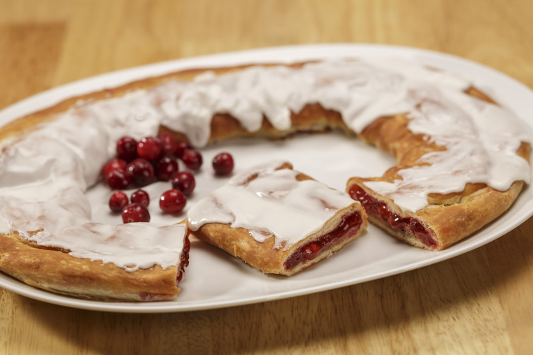 Cranberry Kringle on white plate with a scattering of cranberries.