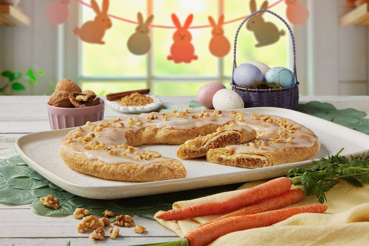 Carrot Cake Kringle on a white plate with carrots and walnuts near the kringle.