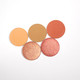 a set of five complimentary peachy and orange eye shadows.