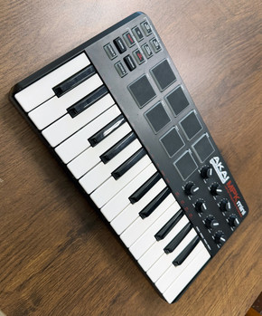 Angled view of the original Akai MPK mini showing the 25-key keybed, 8 MPC pads, and 8 assignable control knobs