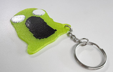 This playful Green Gooey keychain, inspired by the iconic ModWiggler mascot is 3D printed in vibrant green with layered black and white details.