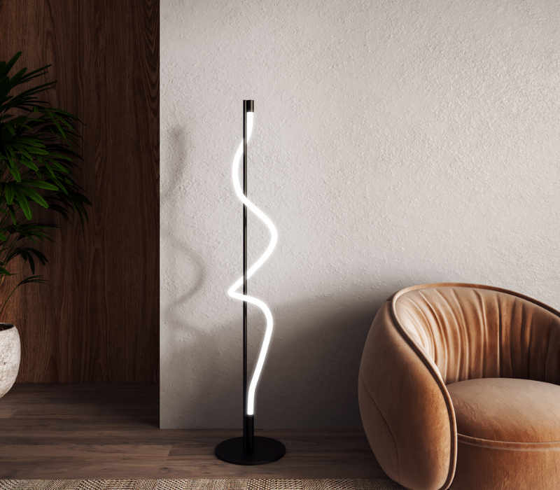 The Cursive Floor Lamp by Kuzco Lighting styled in a sitting room next to a modern peach colored chair.