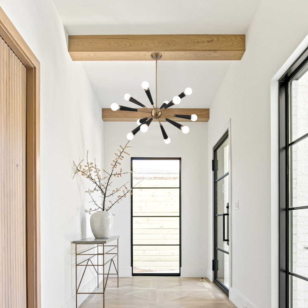 A modern-styled entryway with the Zodiac chandelier in Black and Brass installed on a wooden beam.
