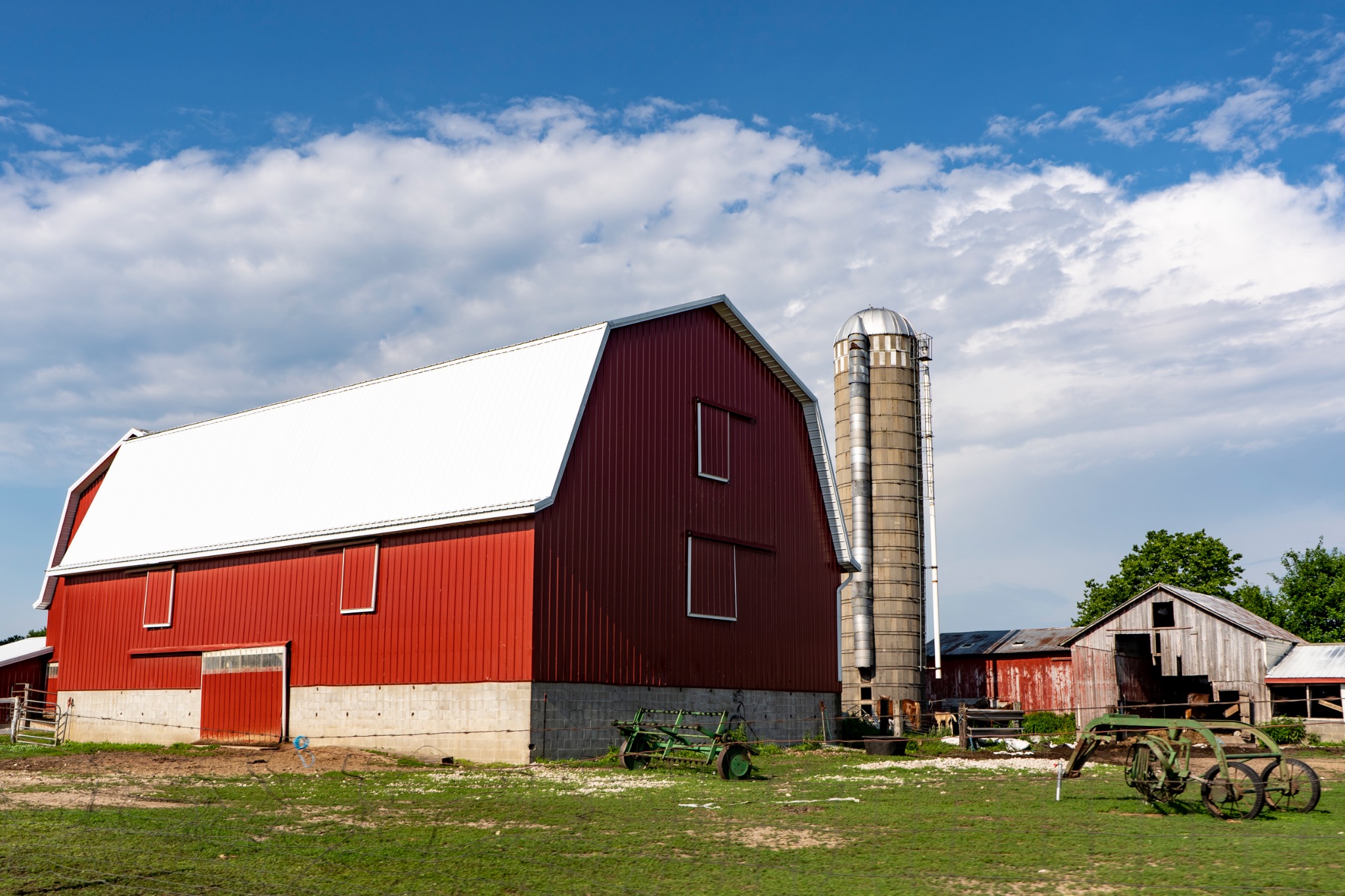 A red barn and silo under a blue sky