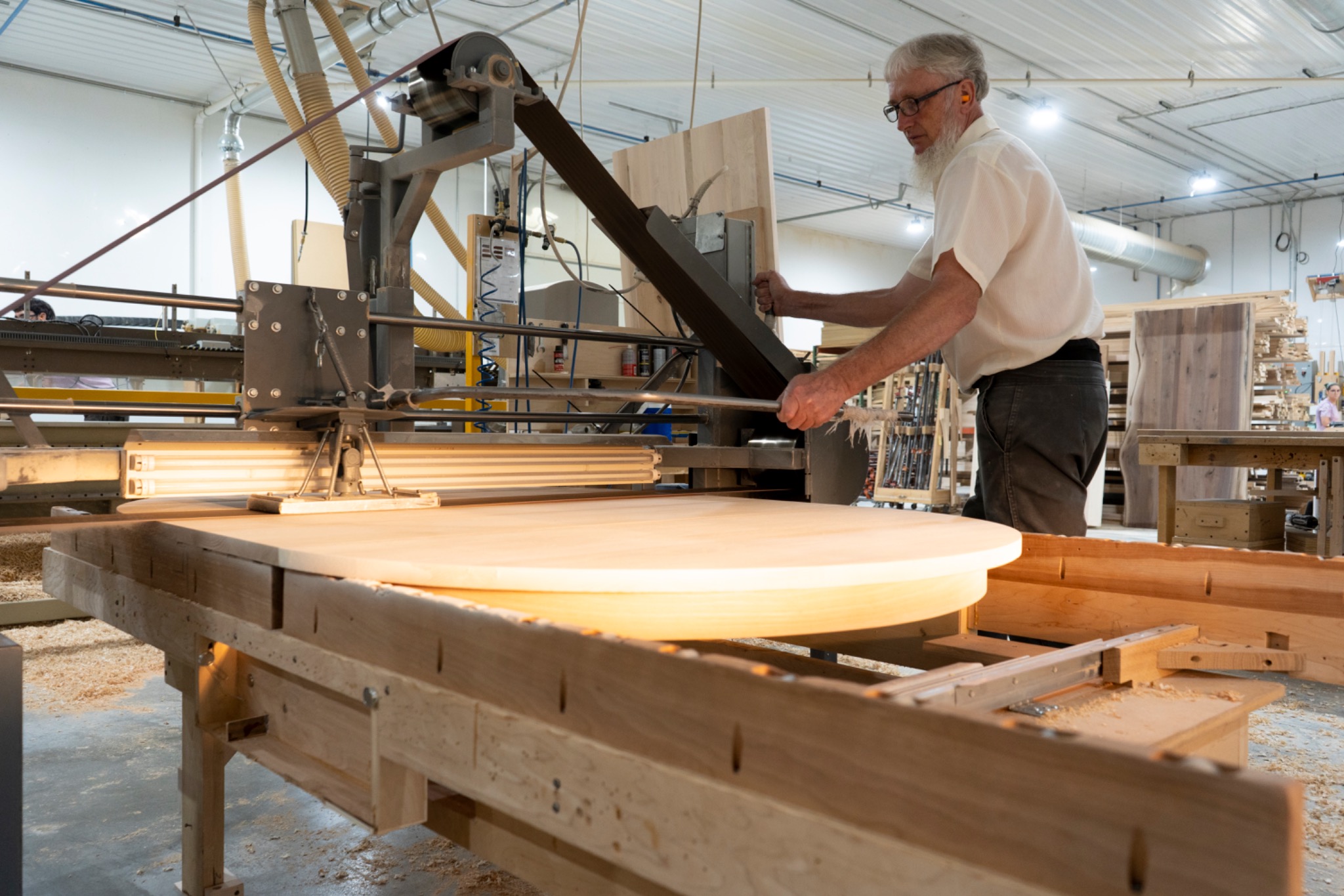A round wooden tabletop supported at a workshop station