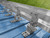 Double bar snow guard system installed on blue exposed fastener metal roof with galvanized mounting brackets