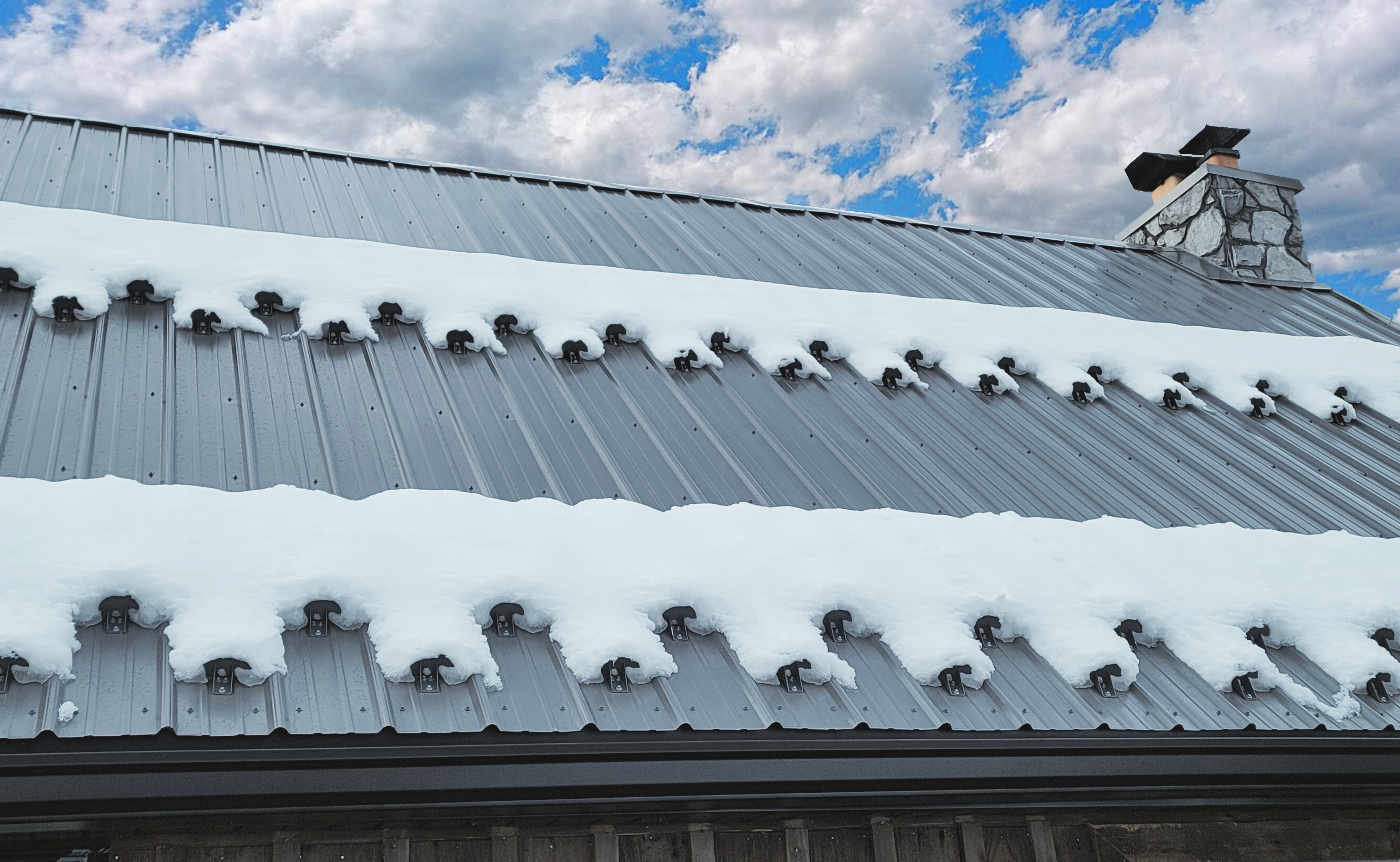 Kodiak SnowCatcher Snow Guards On Metal Roof With Snow and Blue Cloudy Sky