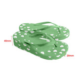 Green flip-flops with white heart patterns, featuring a textured surface and a slight rise in height.