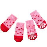 Pet socks in pink and red with heart patterns and non-slip grips on the bottom. Includes four individual socks.