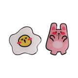 A pink rabbit-shaped acrylic phone pop holder and a white egg-shaped holder with a smiling face, both featuring bold outlines.
