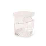 A clear glass whiskey tumbler with a unique sculpted design, featuring a logo.