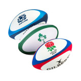 Three stress rugby balls in blue, green, and red, featuring different logos on each.