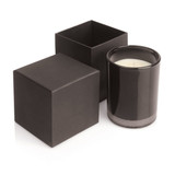 A black soy wax candle in a glass holder, accompanied by two matching black boxes. One box is open.