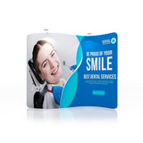 A blue and white S-shaped tension fabric display wall featuring a smiling woman receiving dental care and a logo.