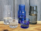 A drink bottle set featuring a clear glass carafe, blue carafe, and matching tumblers in various shades of blue and clear.