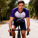 A cyclist wearing a purple and white unisex sublimated stand collar raglan short sleeves cycling jersey on a road.