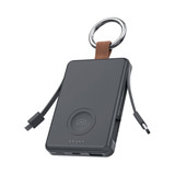 A black power bank with a key ring, featuring built-in charging cables and a circular wireless charging pad. A black power bank with a key ring, featuring built-in charging cables and a circular wireless charging pad.