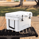A white 31L cooler box with black handles, resting on a wooden bench in a park setting.