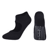 A pair of black yoga socks featuring an open top design and dotted grip on the soles. They have a logo.