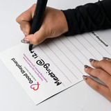 A magnetic whiteboard in white, being written on with a black marker. It has a logo and lined sections.