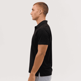 A black polo shirt displayed on a model from the side, featuring a subtle logo on the chest.