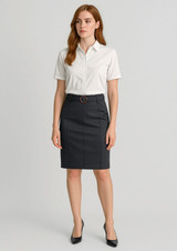 A woman stands in a fitted dark grey mid-waist chino skirt with a belt, paired with a white short-sleeve shirt.