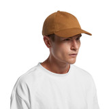 A brown cap with a curved brim and adjustable strap, featuring a logo on the side, worn by a model.