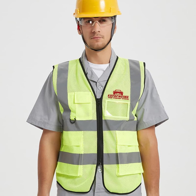 A unisex hi-vis vest in bright yellow with reflective tapes and functional pockets, worn by a person in safety gear.