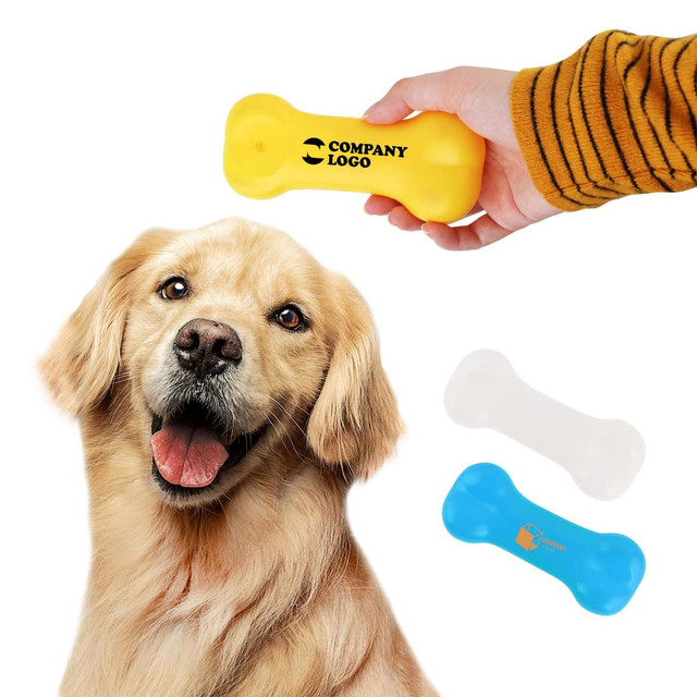 A yellow PVC dog bone, alongside blue and white versions, held near a smiling golden retriever. The product has a logo.