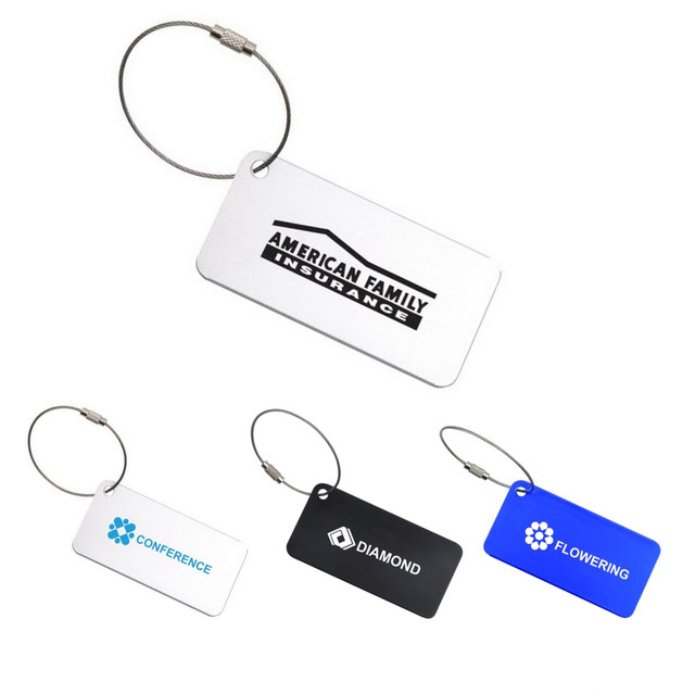 A collection of square aluminium luggage tags in white, black, and blue, each with a metal loop and branding.